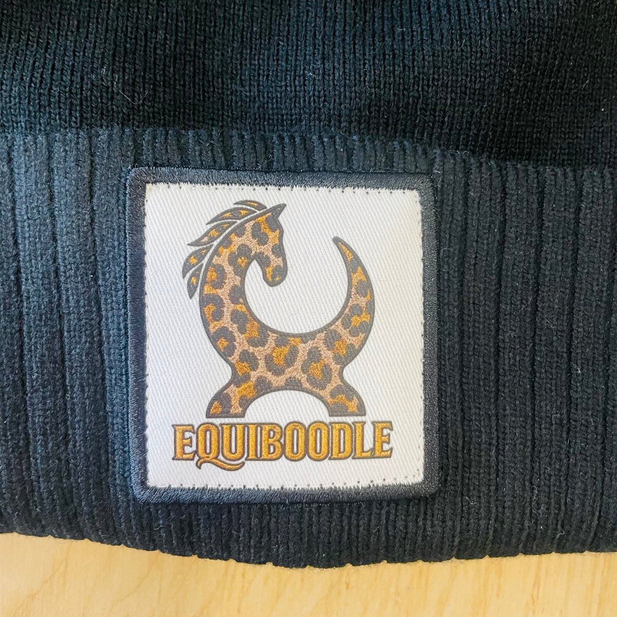 Close-up of Equiboodle gold leopard horse patch on bobble hat