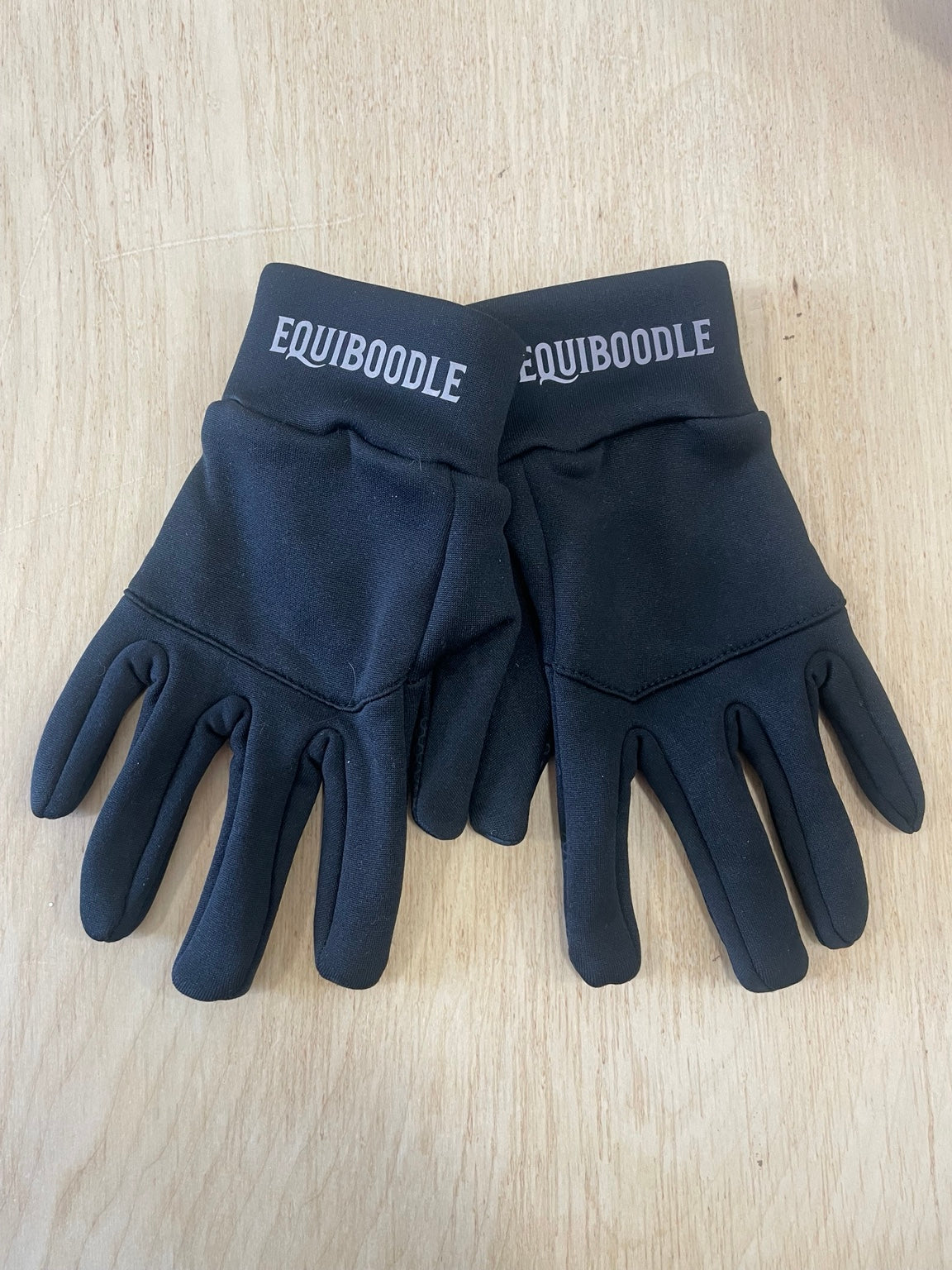 Pair of Equiboodle reflective softshell gloves showing logos on both cuffs