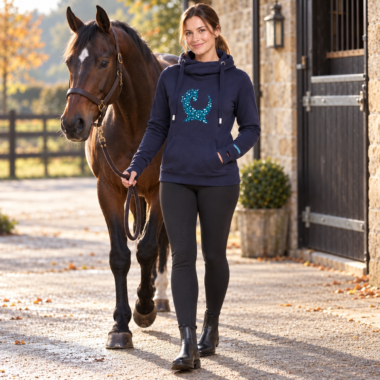 Model wearing the Equiboodle Teal Leopard Vixen hoodie at an equestrian yard